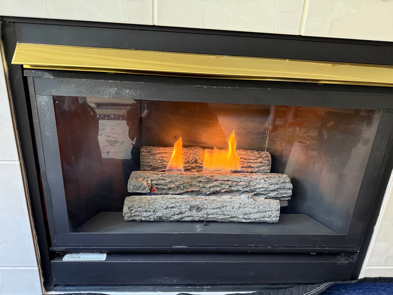 Gas fireplace insert with a black frame, ceramic logs and lit flames