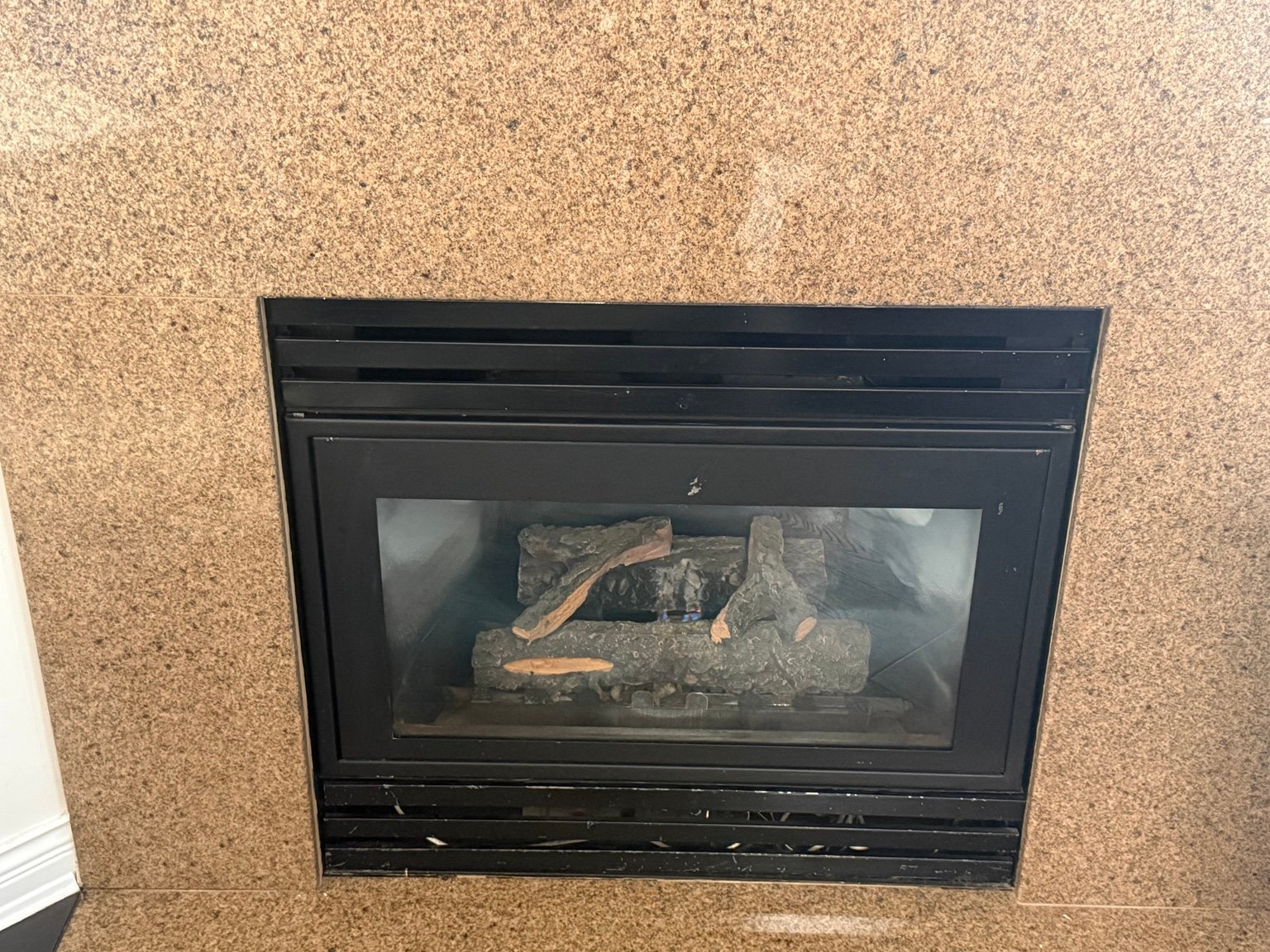 Gas fireplace with a black framed glass front in a stone surround